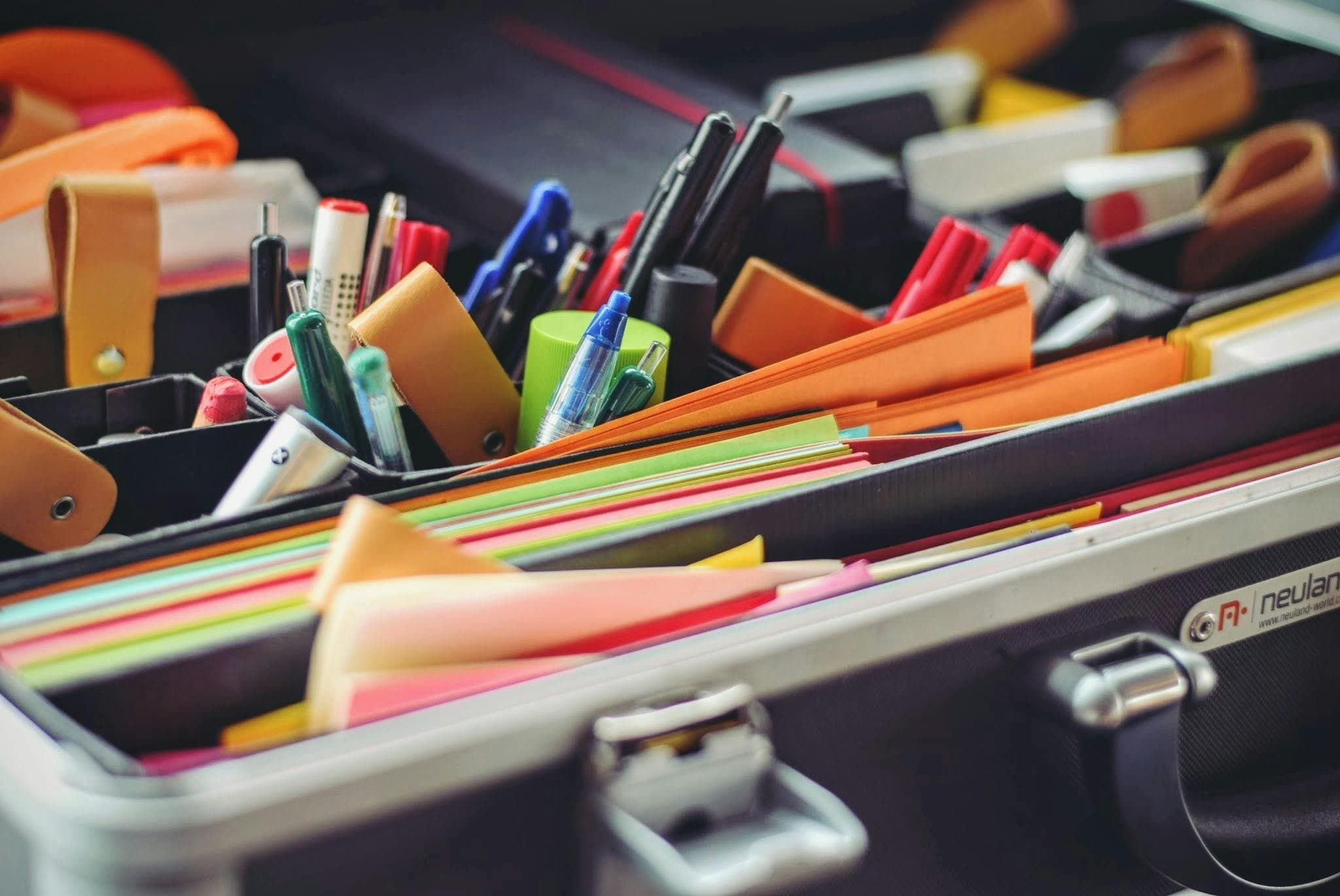An open case packed with pens, markers and coloured paper