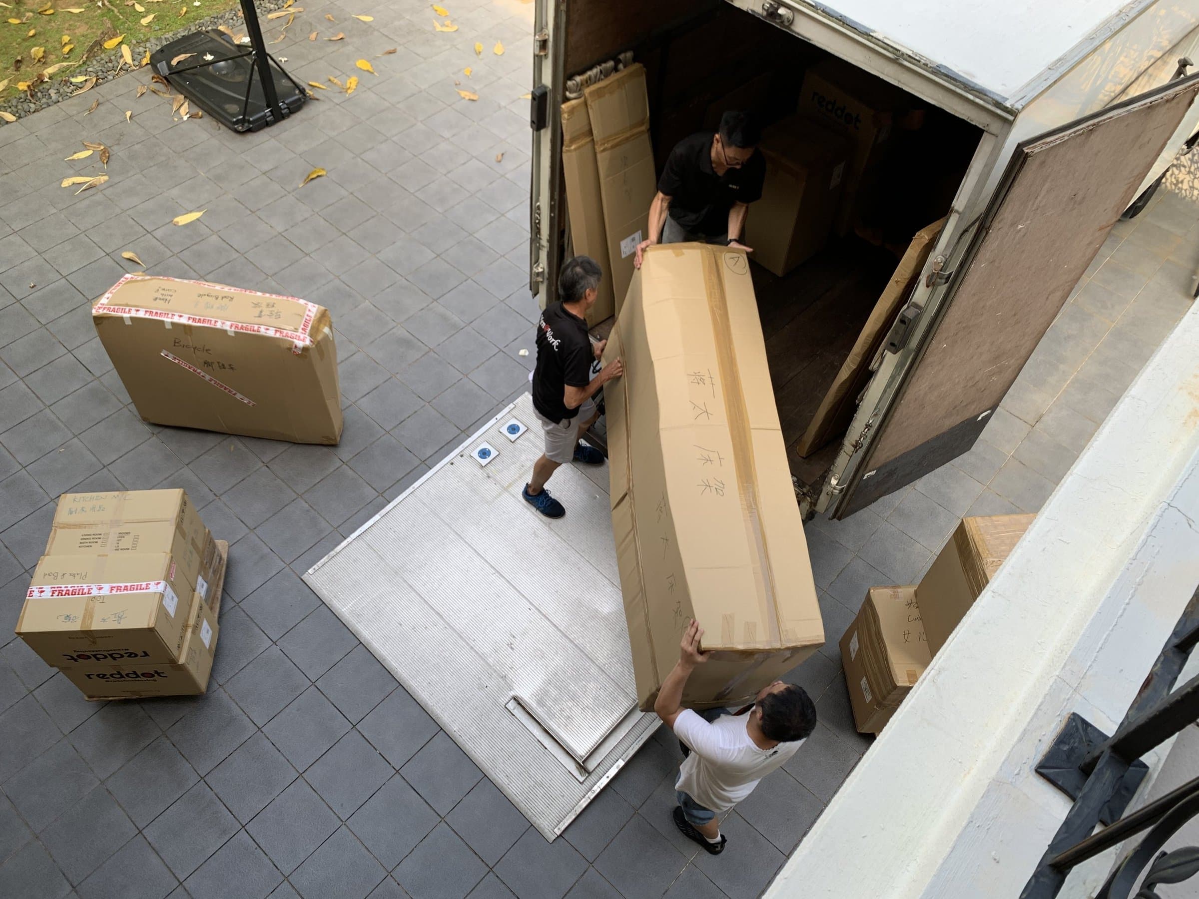 Movers unloading a large boxed item from a truck, seen from above