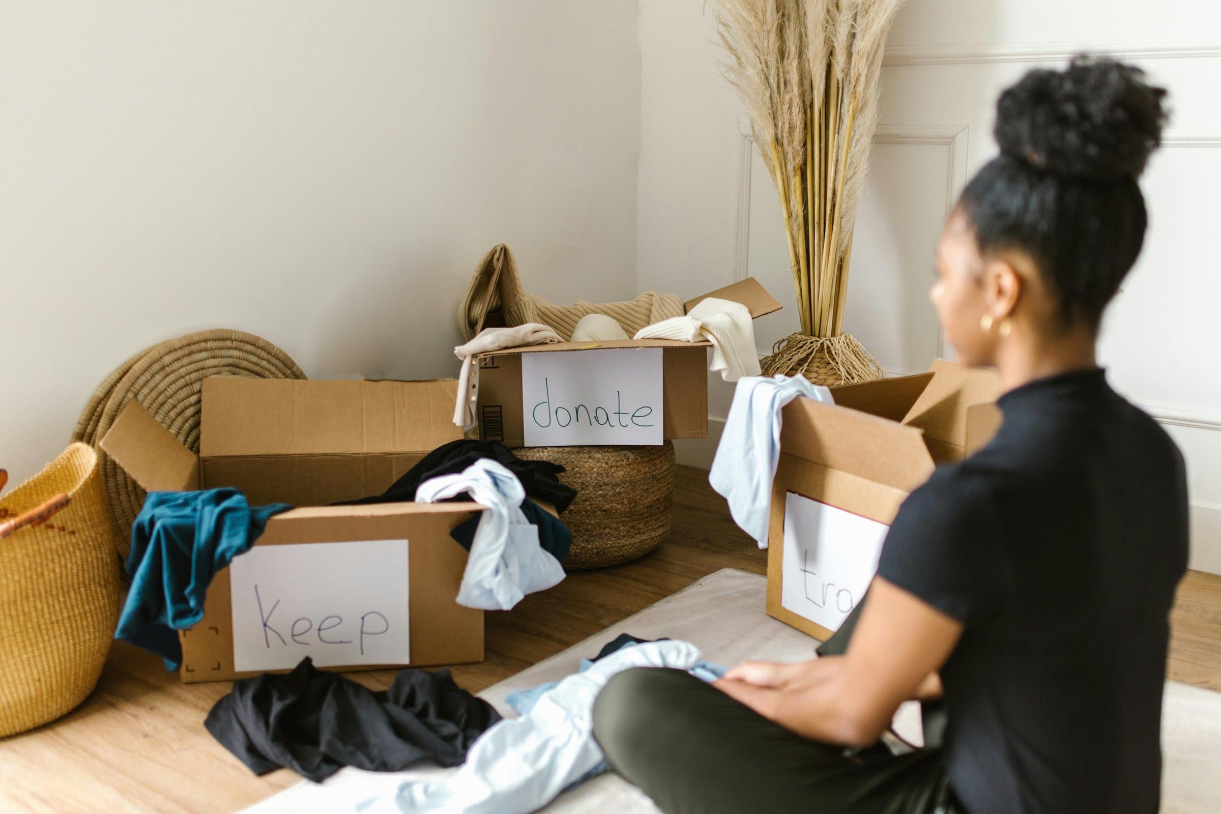 A woman sorting clothes into boxes labelled “Keep” and “Donate”