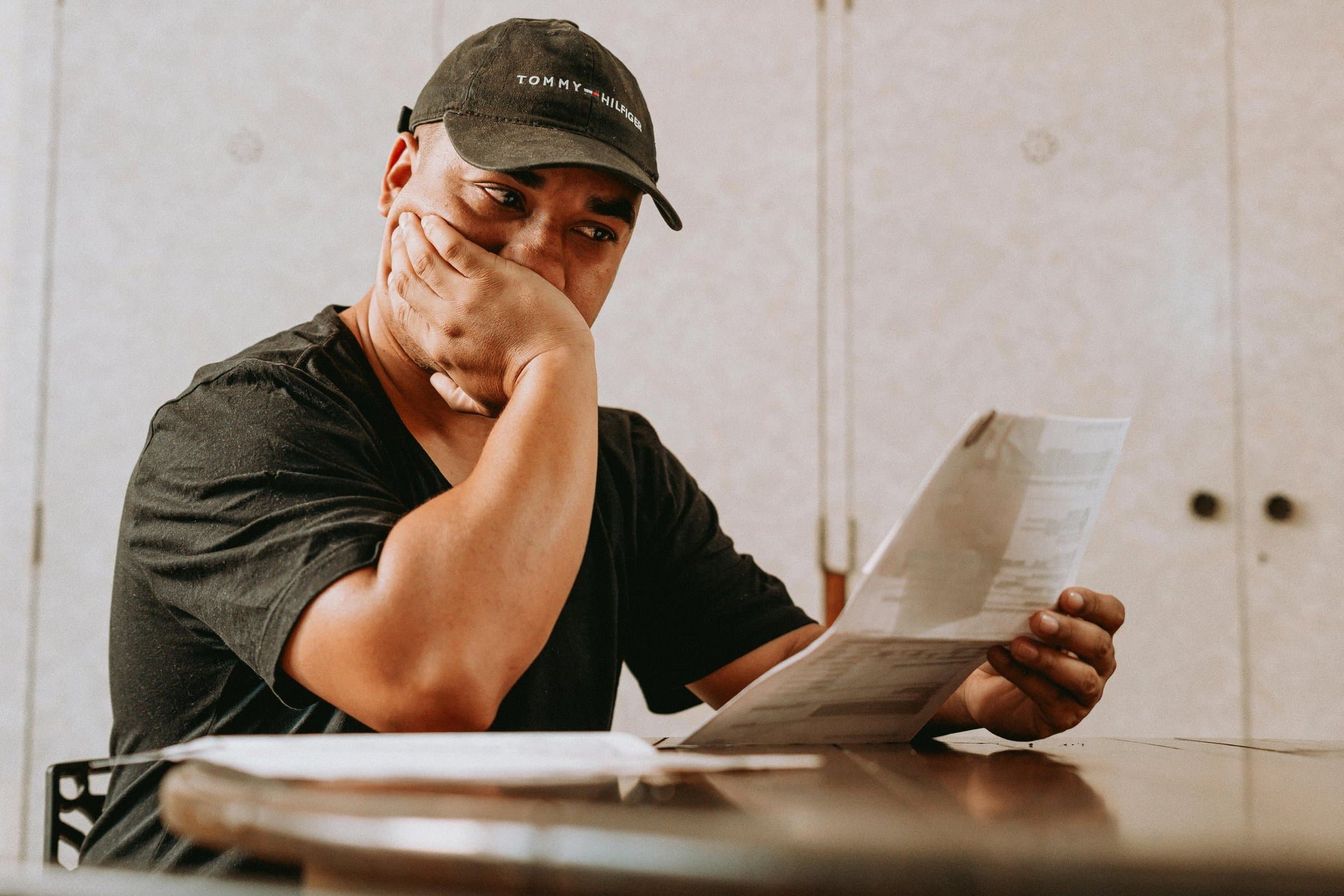 A man reading a document with his hand over his mouth, looking concerned