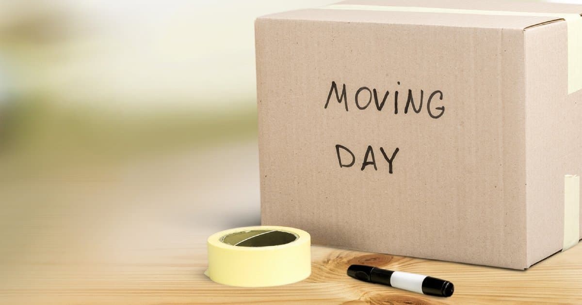 A cardboard box labelled “Moving day” with tape and a marker