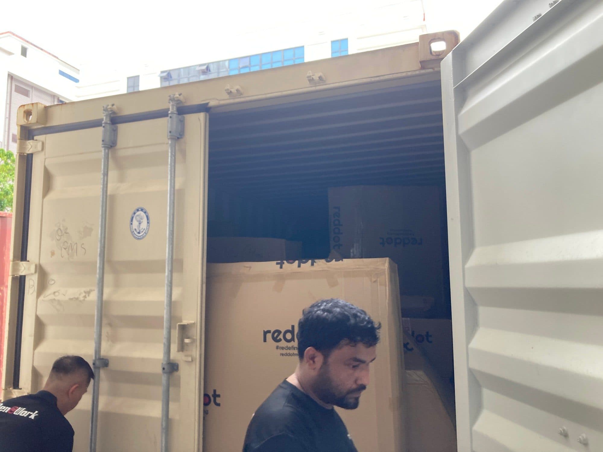 Reddot movers at the doors of a shipping container packed with Reddot boxes