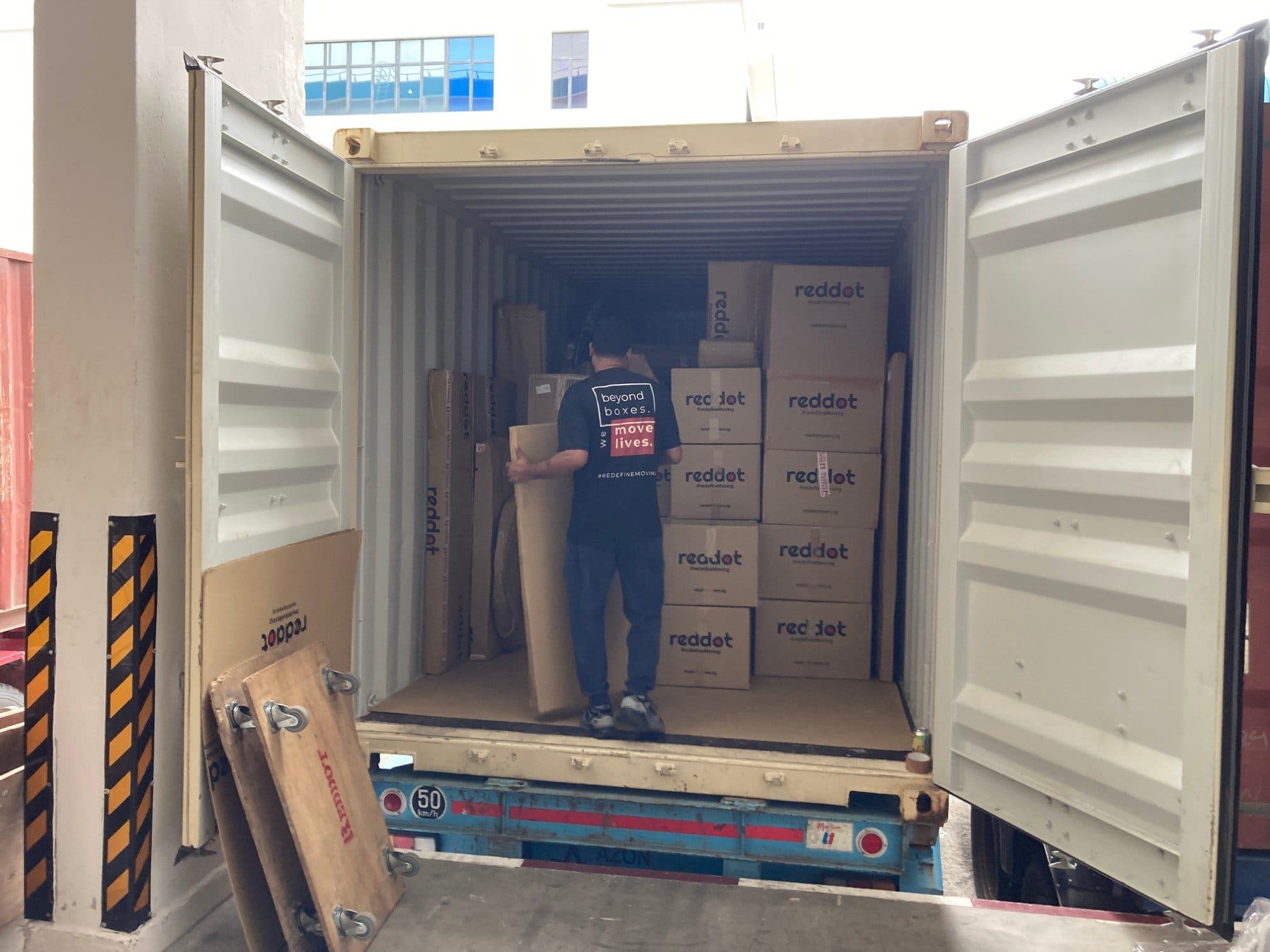 A Reddot mover loading a shipping container stacked with Reddot boxes