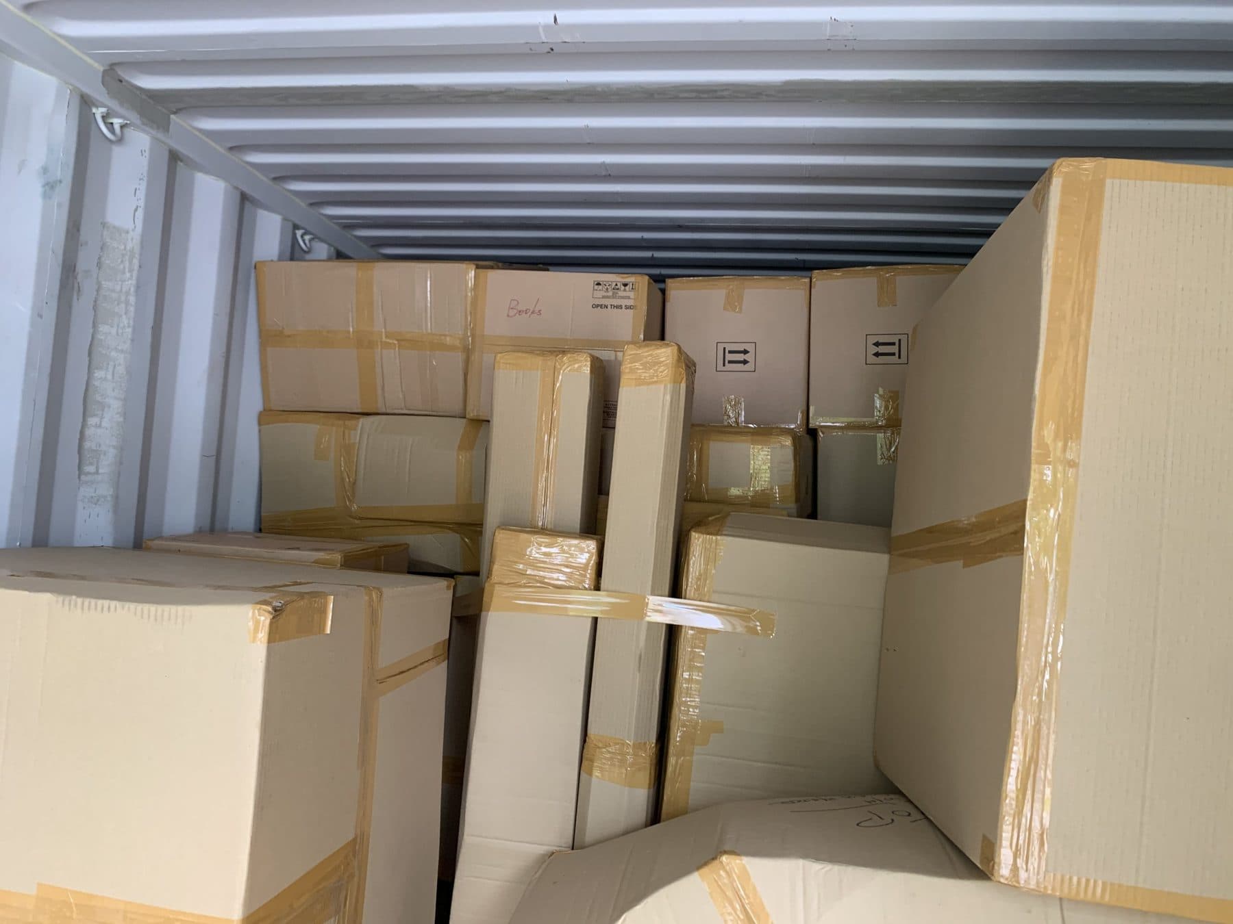 Taped boxes of different sizes packed tightly inside a shipping container