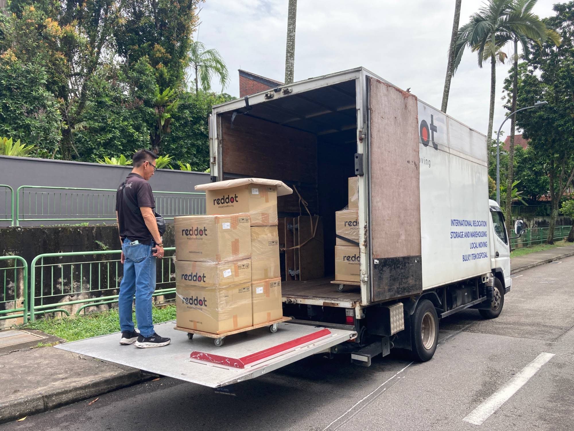 A Reddot mover beside a trolley of wrapped Reddot boxes on a truck's tail-lift