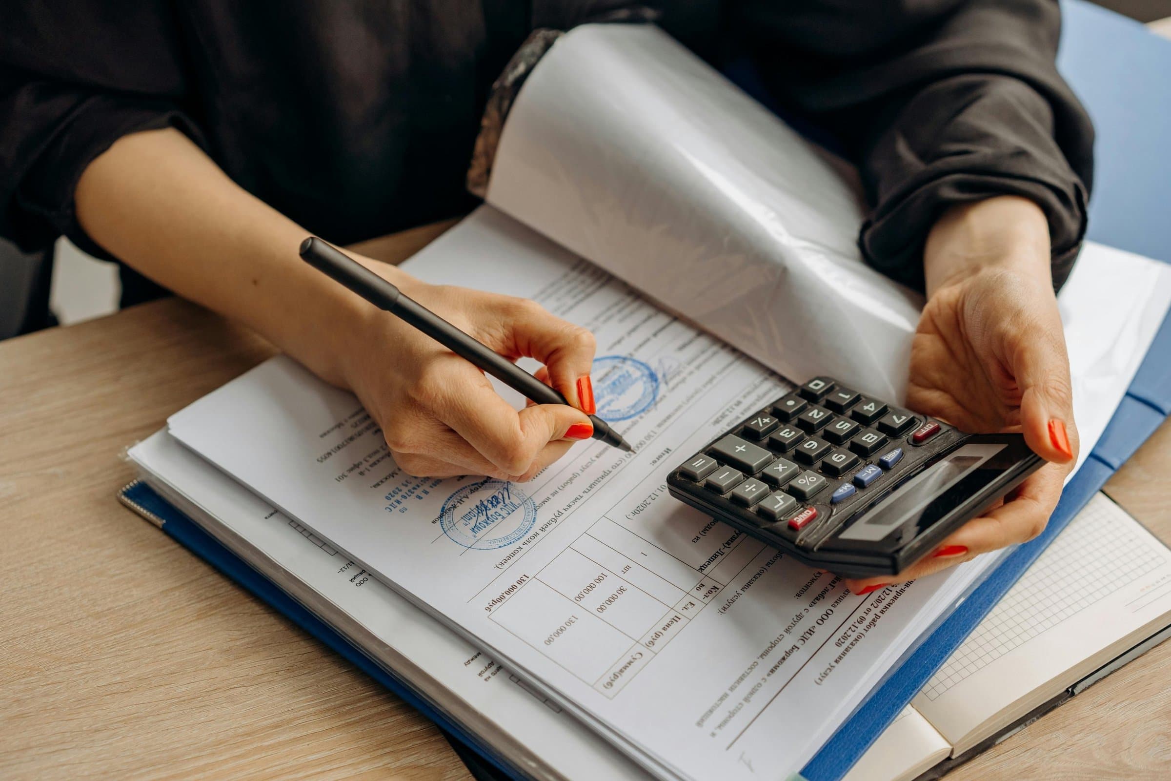 A person going through paperwork with a calculator and pen