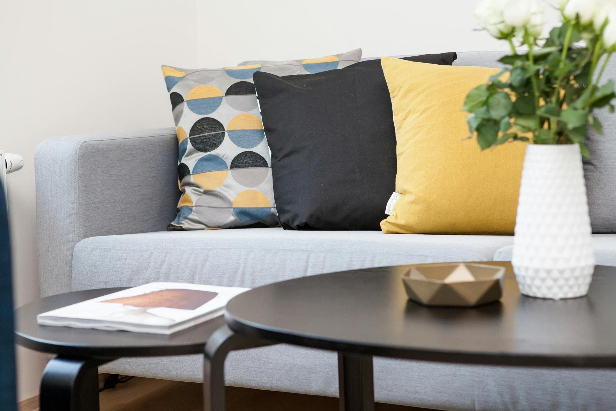 A grey sofa with patterned cushions beside a round coffee table