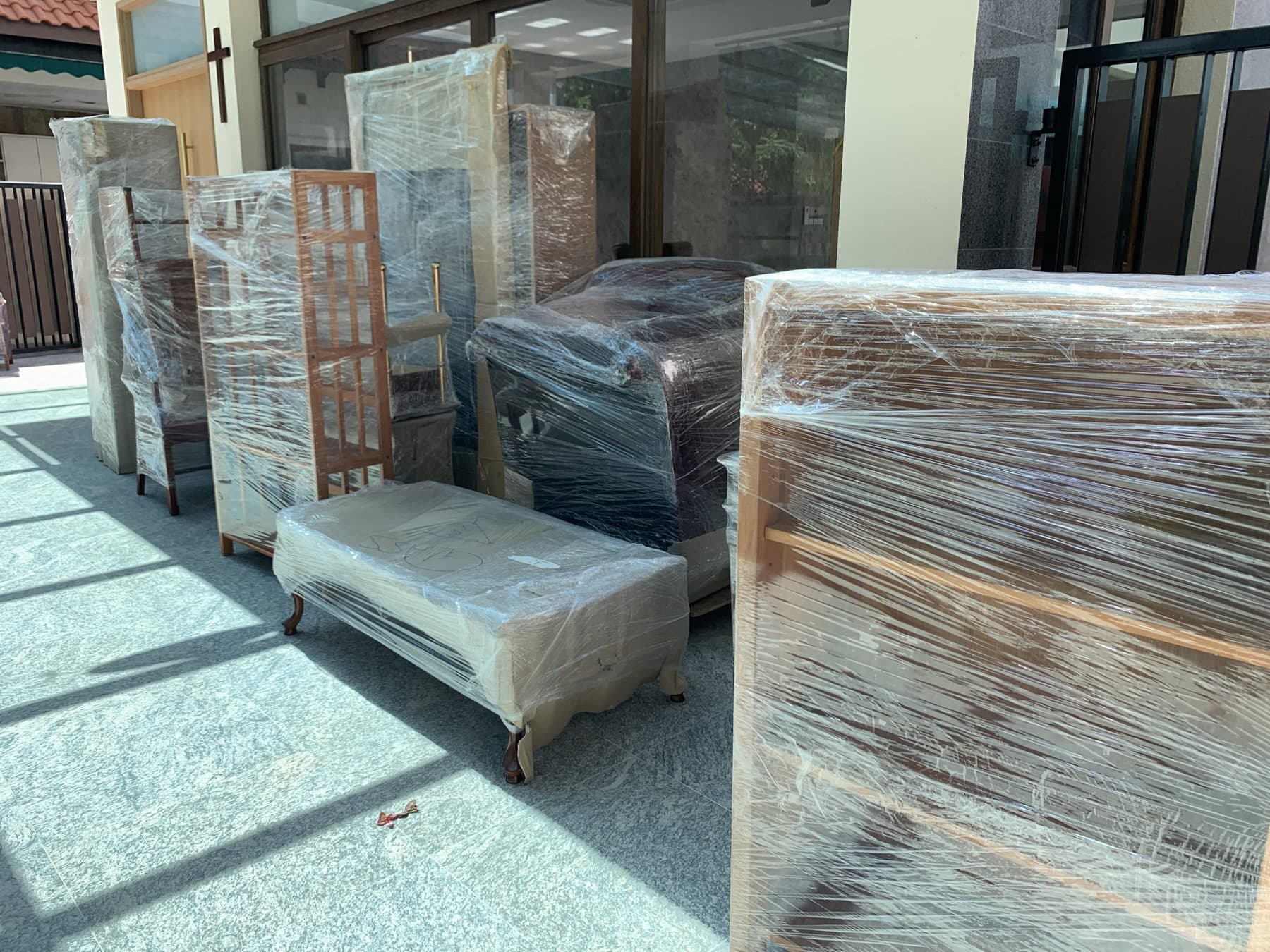 Furniture wrapped in film, lined up outside a house